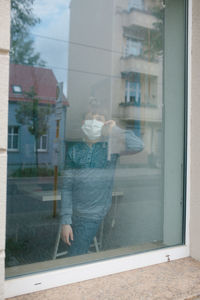 Woman standing by window of building