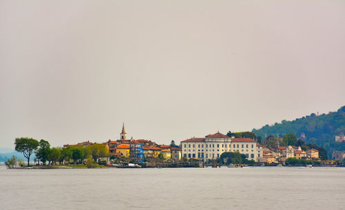 Buildings by sea against clear sky