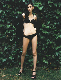 Portrait of beautiful model standing in lingerie against plants
