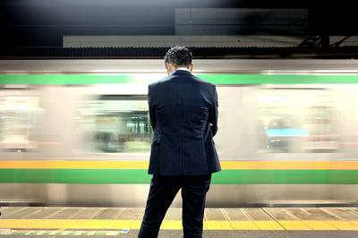 Rear view of man standing at railroad station