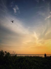 Low angle view of airplane flying in sky during sunset