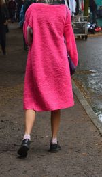 Low section of woman in pink dress walking on sidewalk
