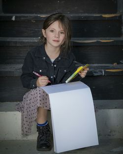 Portrait of smiling girl drawing in book