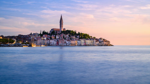 View of buildings at waterfront against cloudy sky