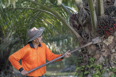 Man wearing hat working by tree at farm