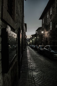 Empty alley amidst buildings in city at night