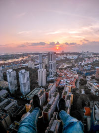 Low section of man over cityscape during sunset
