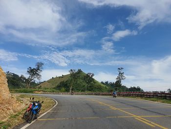 People riding motorcycle on road against sky