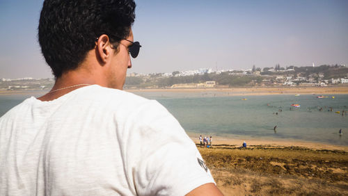 Rear view of man looking at sea against sky