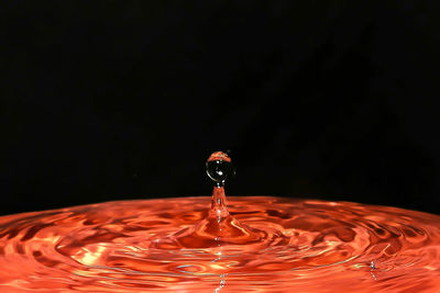 Close-up of orange drop against black background