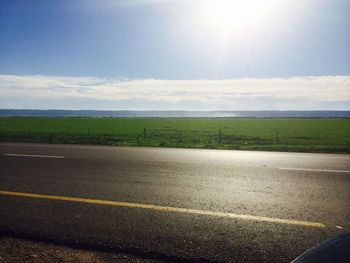 Road by field against sky