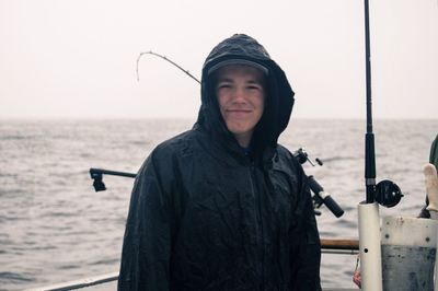 Portrait of man wearing raincoat against sea