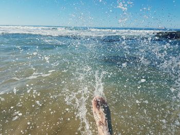 Low section of person foot splashing water at beach