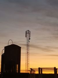 Low angle view of silhouette factory against sky during sunset