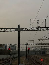 Railroad tracks by bridge against sky at sunset