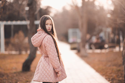 Portrait of stylish kid girl 10-12 year old with long blonde hair wear casual jacket in park outdoor