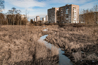 Scenic view of river by buildings against sky