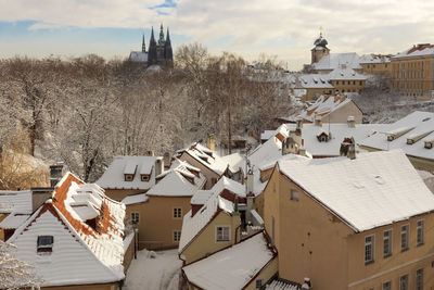 Prague castle with the rooftops of buildings of new world area in winter with snow.