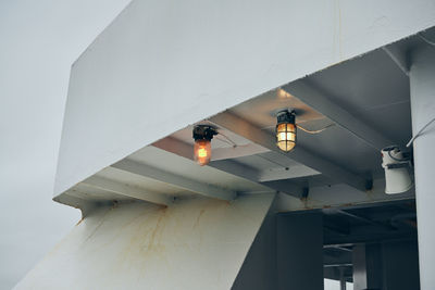 Low angle view of illuminated light hanging on ceiling of building