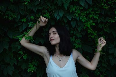 Young woman standing against plants