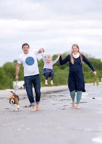 Full length of happy family walking at beach