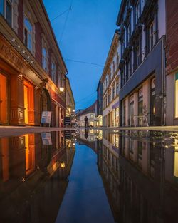 Canal amidst buildings against clear sky at dusk