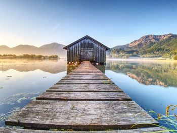 Beautiful morning at lake with traditional wooden boat house. shore of famous mountain alps lake