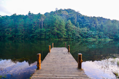 Wooden pier over lake against sky