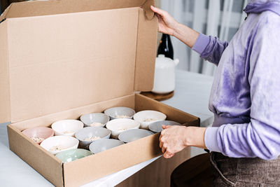Packing homemade oatmeal bowls in cardboard box. person carefully packing multiple bowls