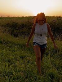 Full length of woman on field against sky during sunset