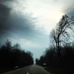 Road amidst trees against sky