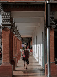 Rear view of women walking on corridor of building