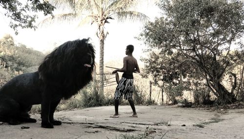 Rear view of man with dog standing against trees