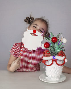 Happy cute little girl near the santa claus face made with pineapple