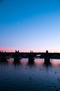 Bridge over river against sky at sunset
