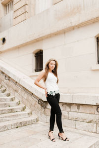Full length portrait of young woman standing on steps