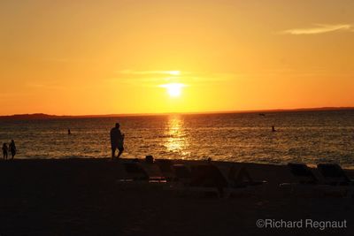 Silhouette people on beach at sunset