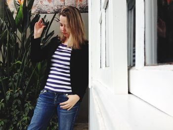 Young woman standing against wall