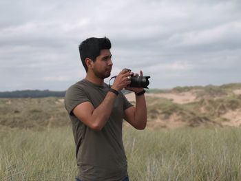 Young man photographing from camera on land