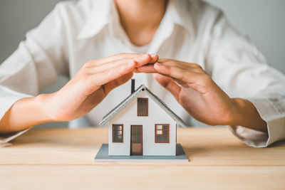 Midsection of businessman holding model house key on table