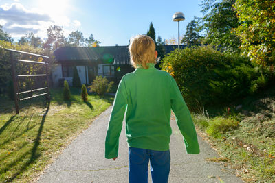 Rear view of woman standing by plants against sky