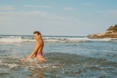 Portrait of young woman standing in sea against sky