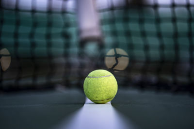 Close-up of tennis ball against net at sports court