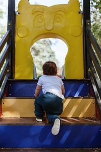 Rear view of baby girl playing on outdoor play equipment at park