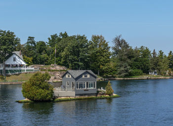 House by lake and buildings against sky