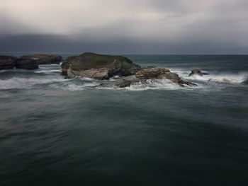 Scenic view of rocks in sea against sky