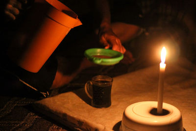 Low section of man holding illuminated candles