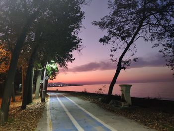 Road by sea against sky at sunset