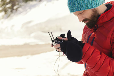 Man using remote control while standing on snow covered field