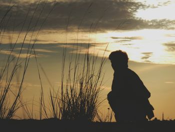 Silhouette man standing on beach against sky during sunset